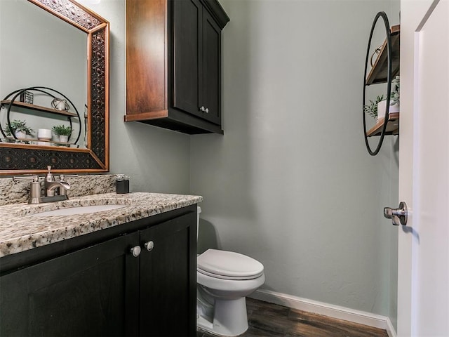 half bathroom featuring baseboards, vanity, toilet, and wood finished floors