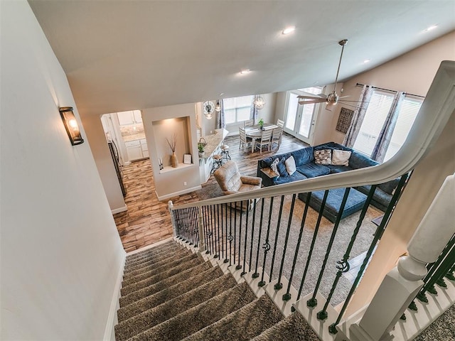 stairs with a ceiling fan, baseboards, recessed lighting, wood finished floors, and vaulted ceiling