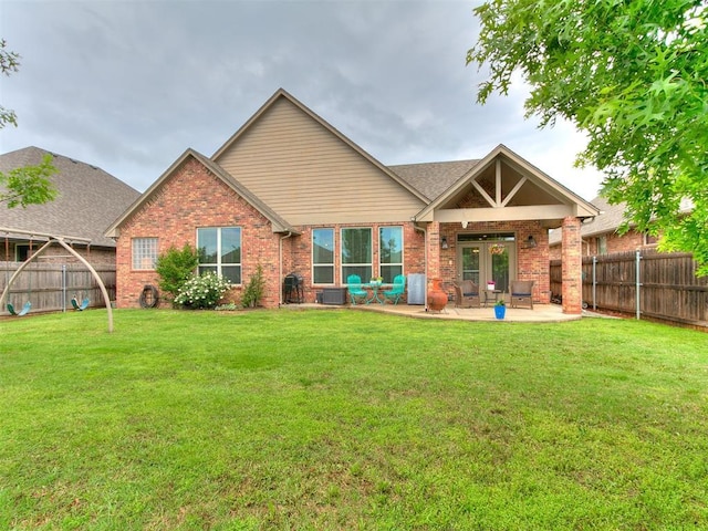 back of property with a lawn, a patio, brick siding, and a fenced backyard
