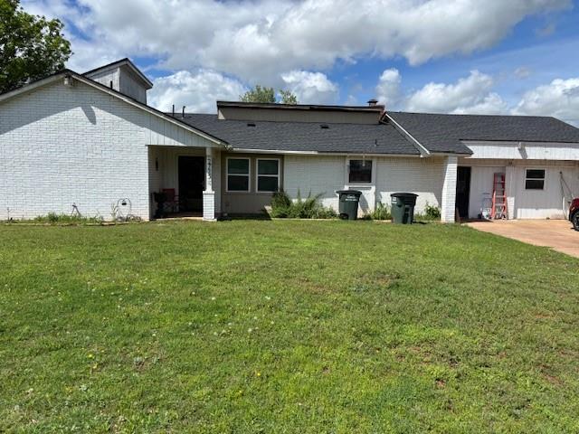 back of property featuring brick siding and a yard