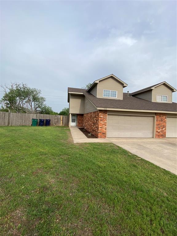 view of front of home featuring a front yard, driveway, brick siding, an attached garage, and fence