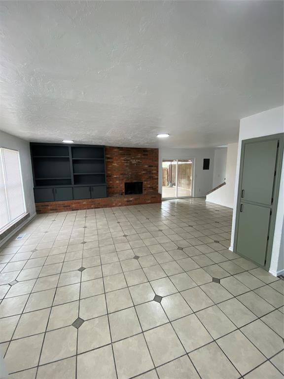 unfurnished living room featuring light tile patterned floors and a fireplace