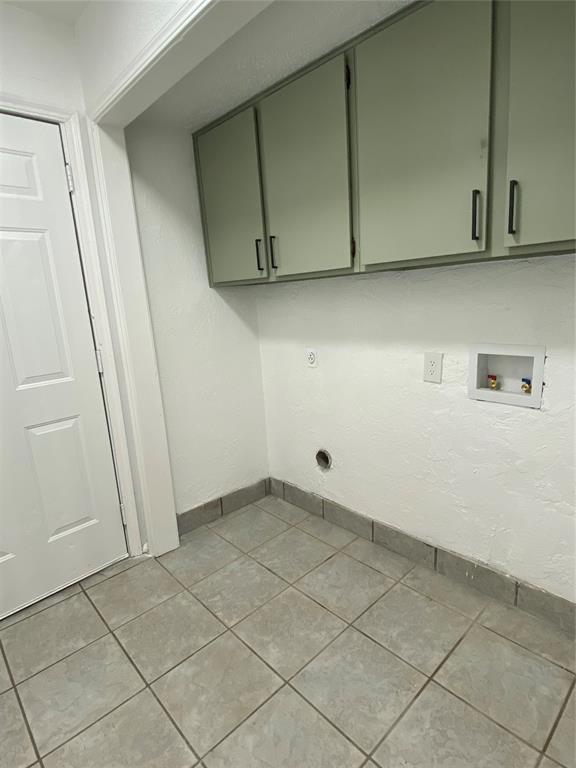 clothes washing area with baseboards, hookup for a washing machine, light tile patterned floors, and cabinet space