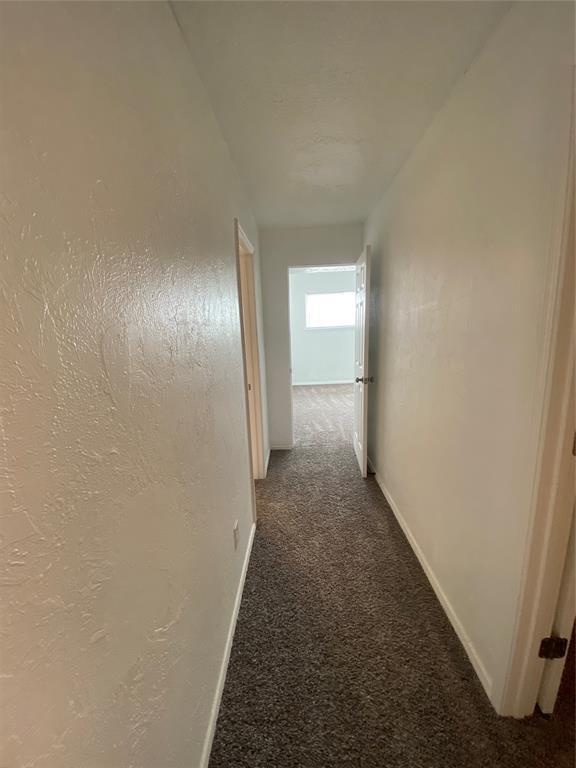 hallway featuring carpet floors and baseboards