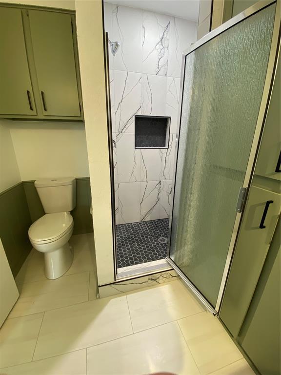 full bath with tile patterned floors, a stall shower, and toilet