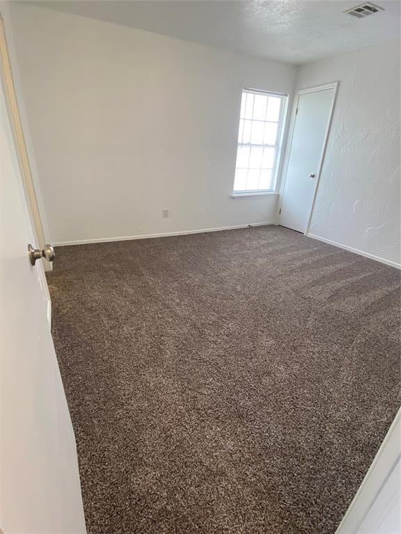 carpeted empty room featuring visible vents and baseboards