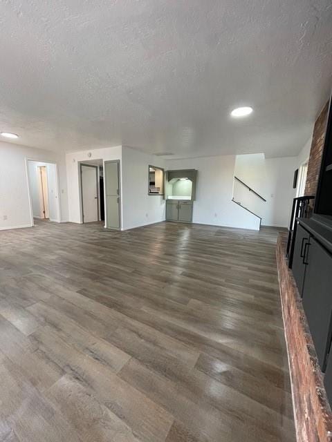 unfurnished living room featuring wood finished floors, a large fireplace, and a textured ceiling