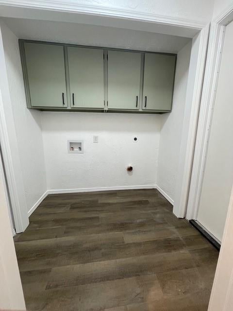 laundry room featuring electric dryer hookup, cabinet space, dark wood-style floors, and baseboards