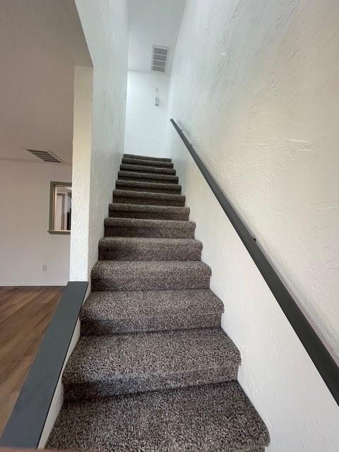 stairs featuring wood finished floors and visible vents