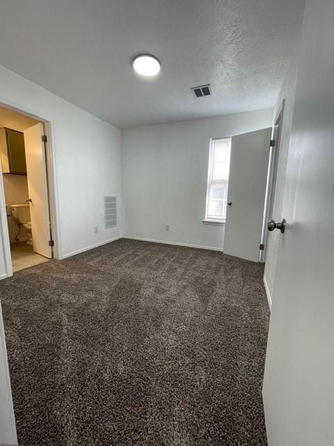 spare room with carpet flooring, visible vents, and baseboards