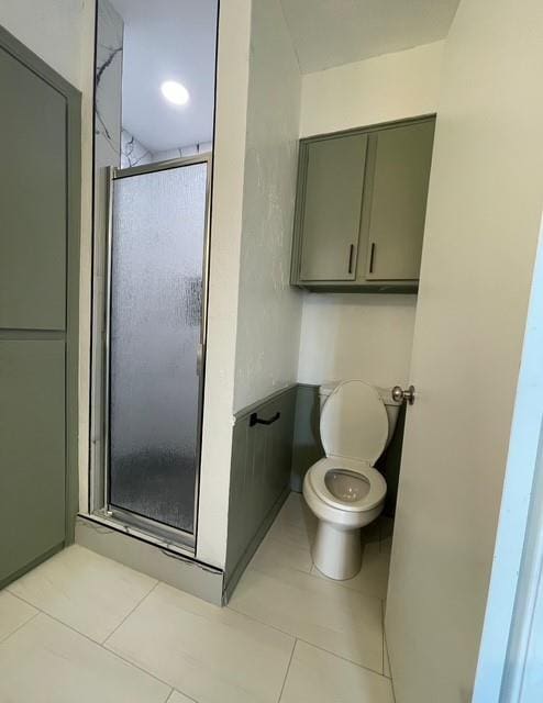 full bathroom featuring toilet, a stall shower, and tile patterned floors