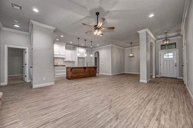 11608 NW 104th St, Yukon, OK 73099 - unfurnished living room with ceiling fan, light wood-type flooring, visible vents, baseboards, and arched walkways
