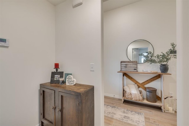 corridor featuring baseboards and light wood-style flooring