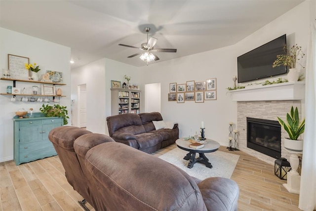 living room with a ceiling fan, baseboards, a glass covered fireplace, and light wood-type flooring