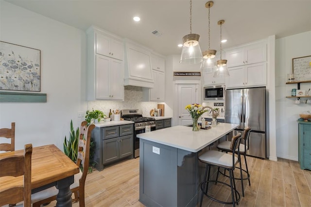 kitchen with decorative backsplash, light countertops, a sink, light wood-style flooring, and appliances with stainless steel finishes