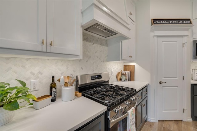 kitchen featuring light countertops, backsplash, custom exhaust hood, and gas range