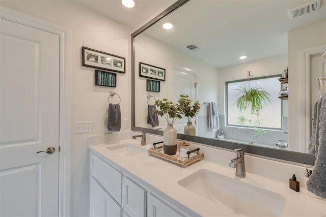 bathroom with visible vents, a sink, and double vanity