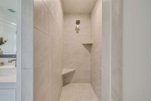 bathroom with vanity, tiled shower, and visible vents