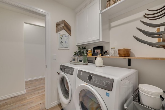 washroom with washer and dryer, light wood-style floors, baseboards, and cabinet space