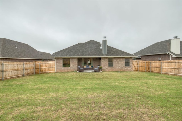 rear view of house with a fenced backyard, a lawn, a chimney, and an outdoor living space
