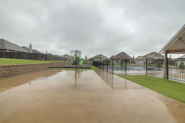 view of sport court featuring a yard, fence, playground community, and a residential view
