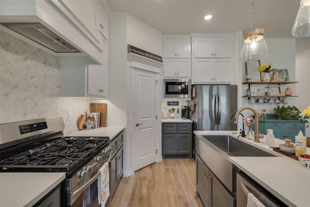 9304 NW 89th St, Yukon, OK 73099 - kitchen with appliances with stainless steel finishes, wall chimney exhaust hood, light wood-style floors, white cabinetry, and light countertops