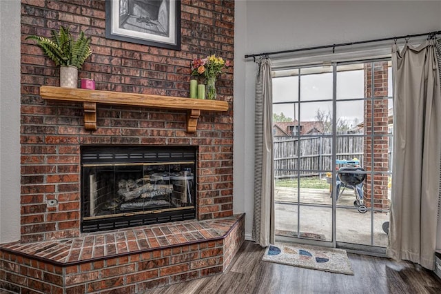 interior space featuring baseboards, plenty of natural light, a fireplace, and wood finished floors