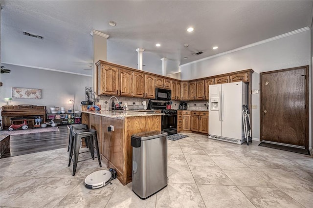 kitchen with decorative backsplash, ornamental molding, black appliances, and a peninsula
