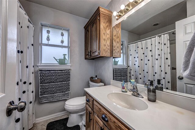 bathroom featuring toilet, baseboards, curtained shower, and vanity