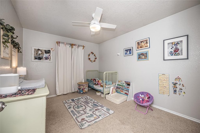 carpeted bedroom with a textured ceiling, baseboards, and a ceiling fan