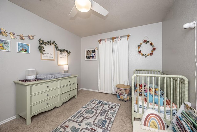 bedroom featuring baseboards, a ceiling fan, a nursery area, and light carpet
