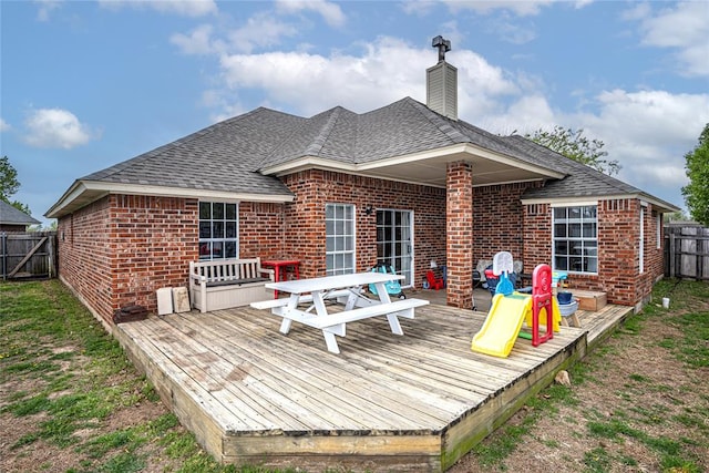 back of house featuring a fenced backyard, a wooden deck, a shingled roof, and brick siding