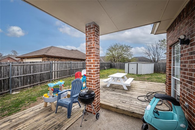 deck with a storage shed, a yard, an outbuilding, and a fenced backyard