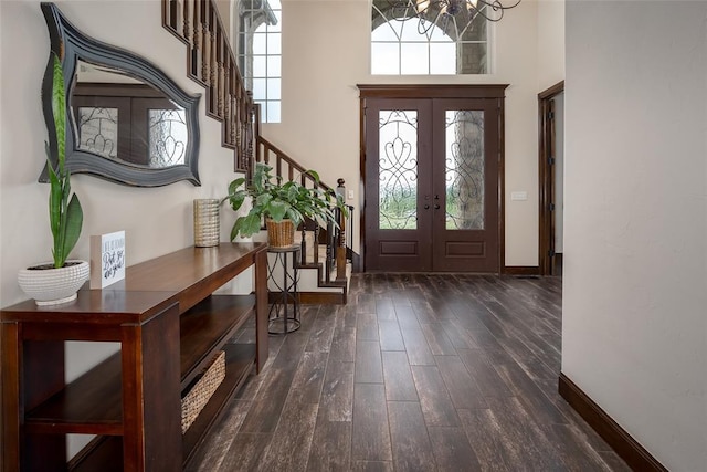 foyer featuring baseboards, a chandelier, plenty of natural light, and dark wood-type flooring