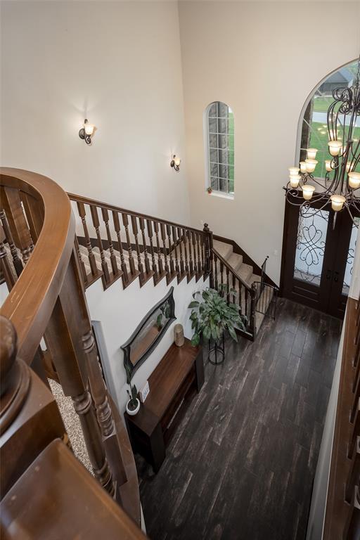 stairs featuring a notable chandelier and wood finished floors