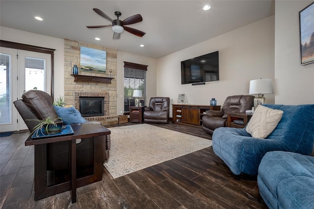 living room featuring ceiling fan, a fireplace, dark wood-style flooring, and a wealth of natural light