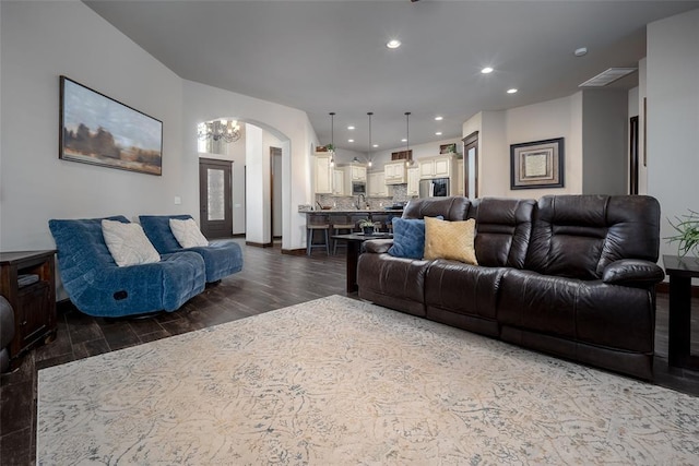 living area with dark wood-style flooring, arched walkways, and recessed lighting
