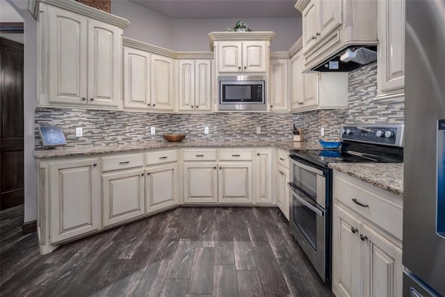 kitchen featuring dark wood-style flooring, appliances with stainless steel finishes, tasteful backsplash, light stone counters, and custom exhaust hood
