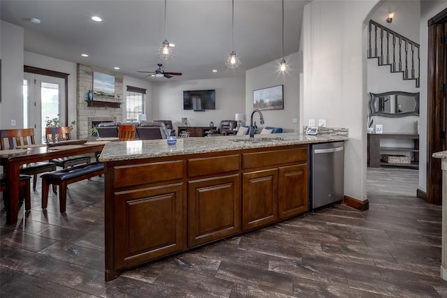 kitchen with ceiling fan, a sink, a fireplace, dishwasher, and a peninsula