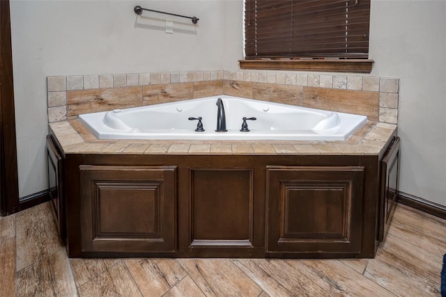 bathroom featuring a tub with jets and wood finished floors