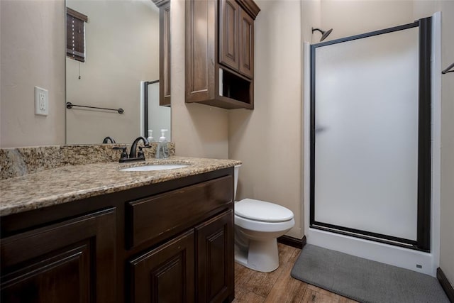 full bathroom featuring vanity, wood finished floors, toilet, baseboards, and a shower stall