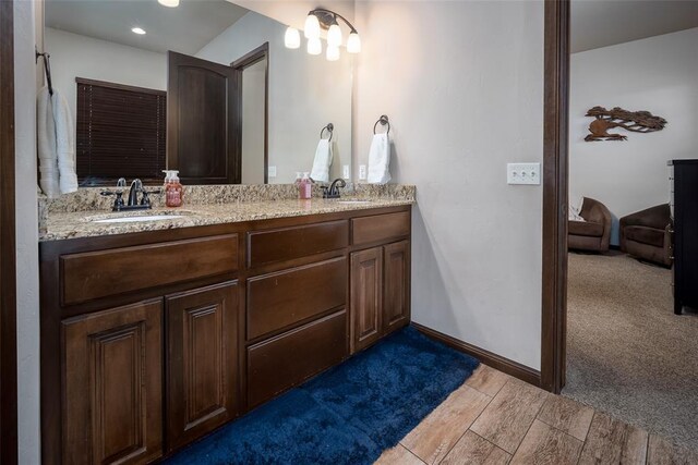 bathroom with a sink, wood finish floors, recessed lighting, and double vanity
