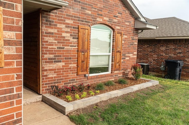 doorway to property with brick siding and roof with shingles