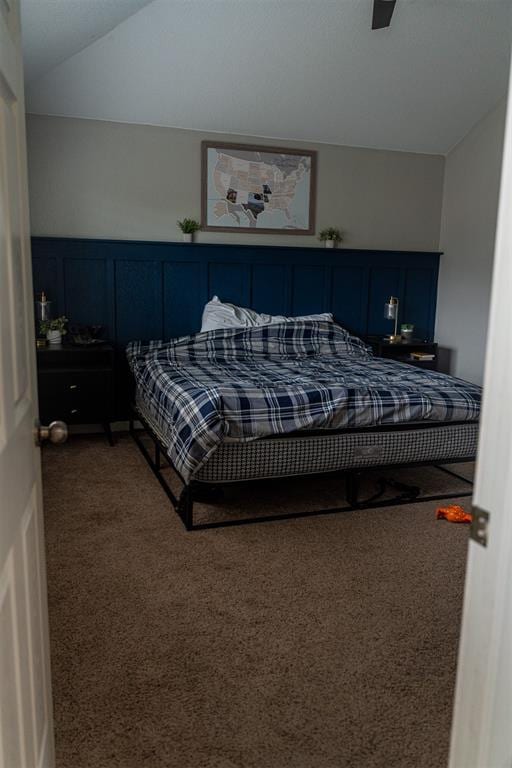 carpeted bedroom featuring wainscoting, ceiling fan, and a decorative wall