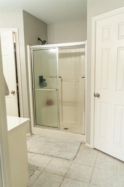 full bathroom featuring tile patterned flooring and a shower stall