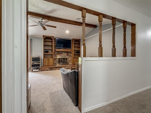 carpeted living area featuring ceiling fan, a fireplace, baseboards, vaulted ceiling with beams, and visible vents