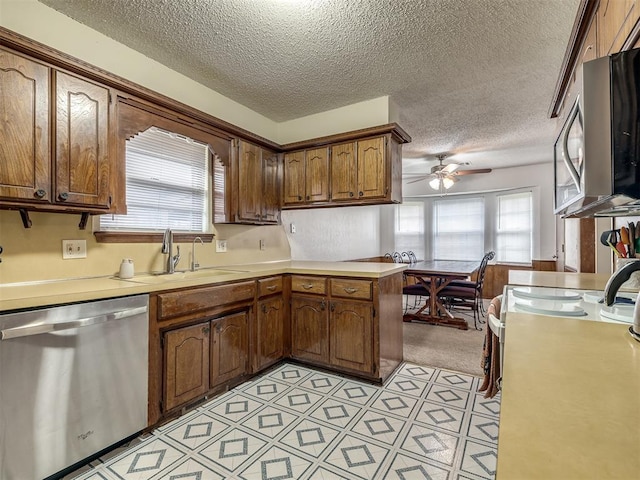 kitchen featuring a sink, a textured ceiling, a ceiling fan, and stainless steel appliances