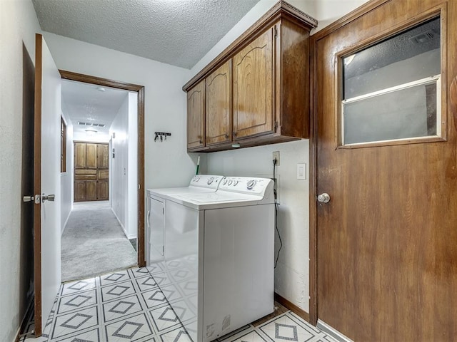 clothes washing area with a textured ceiling, independent washer and dryer, cabinet space, baseboards, and light carpet