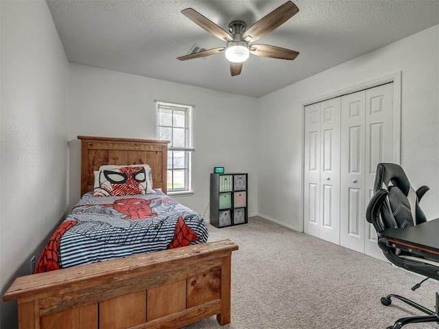 bedroom with a ceiling fan, a textured ceiling, light colored carpet, and a closet