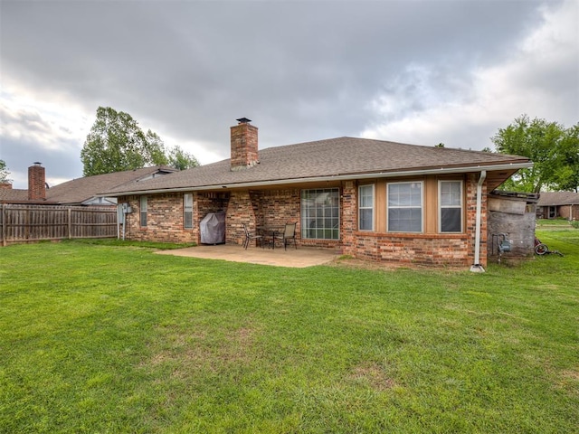 back of property with a patio, brick siding, fence, and a chimney